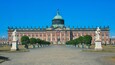 A grand palace with a large dome, symmetrical facade, and statues lining the front.