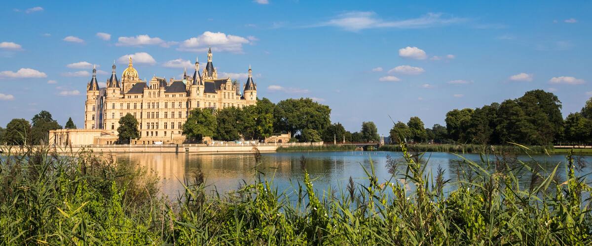 A grand castle by a calm lake surrounded by lush greenery.