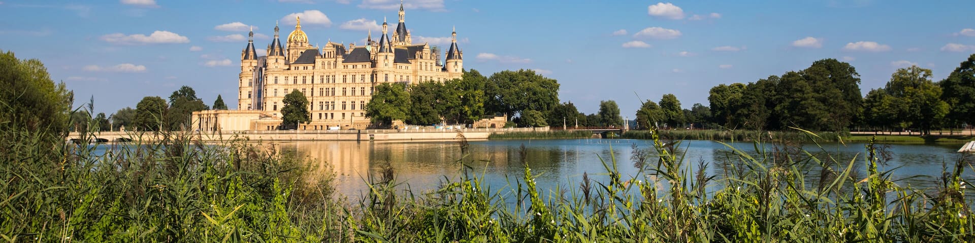 A grand castle by a calm lake surrounded by lush greenery.