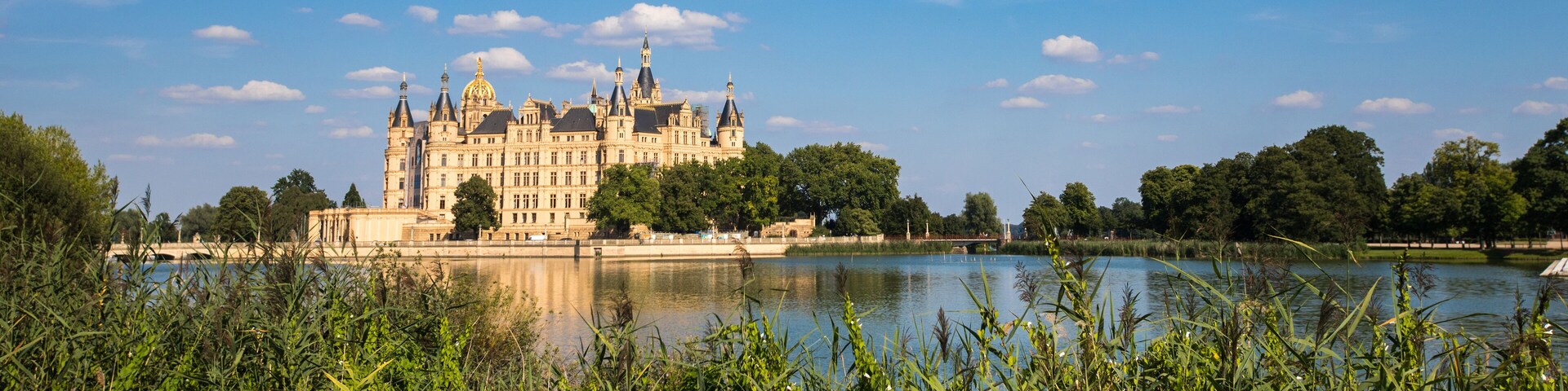 A grand castle by a calm lake surrounded by lush greenery.