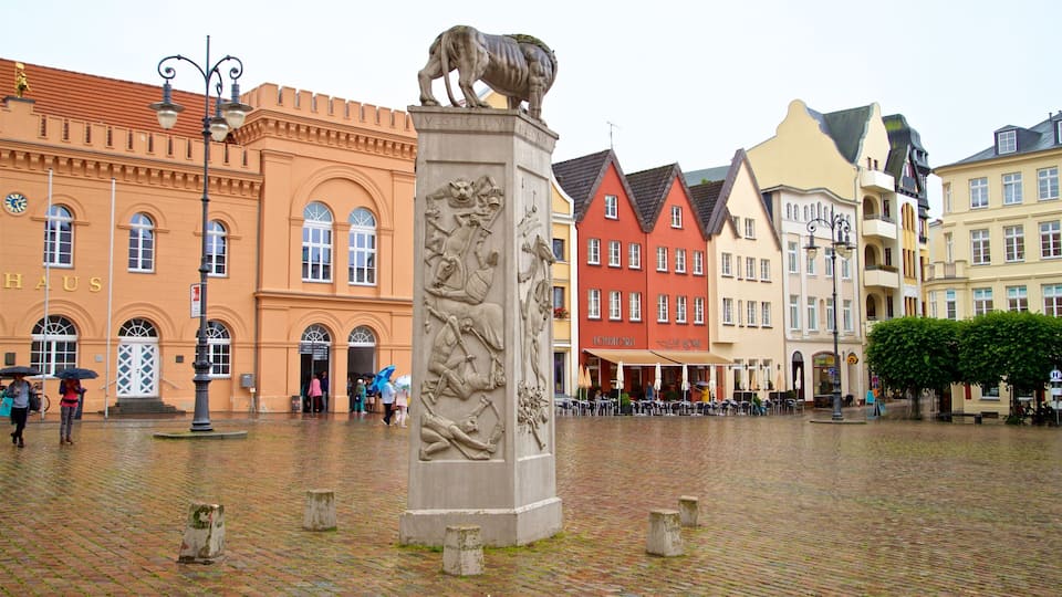 Una plaza adoquinada con una estatua de león, edificios históricos y una cafetería 'Konditorei'.