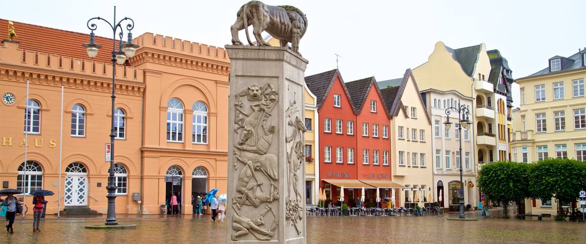 A cobblestone square with a lion statue, historic buildings, and a 'Konditorei' cafe.