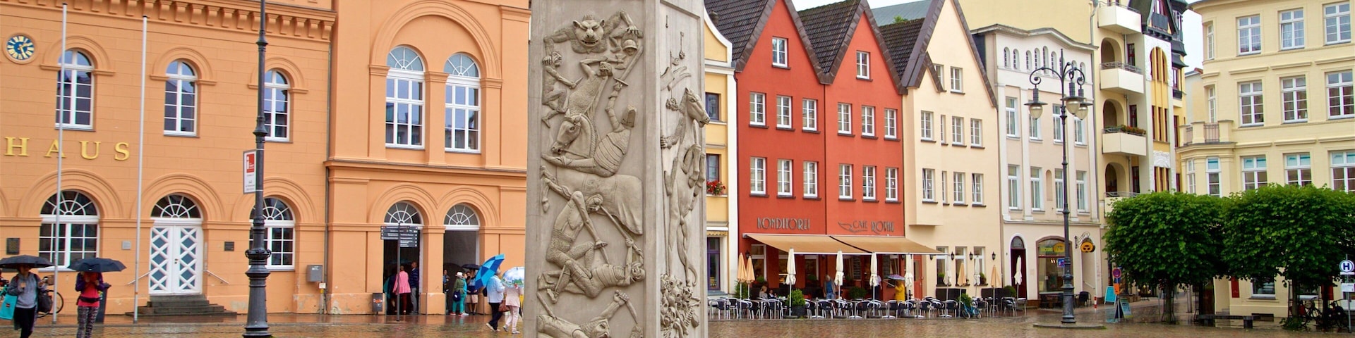 A cobblestone square with a lion statue, historic buildings, and a 'Konditorei' cafe.