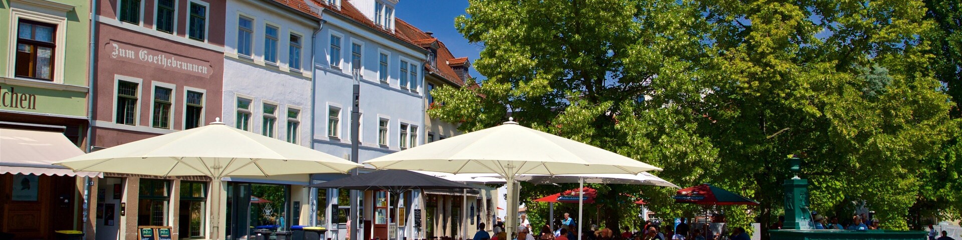 Outdoor cafe seating with umbrellas, cobblestone pavement, and historic buildings in the background.