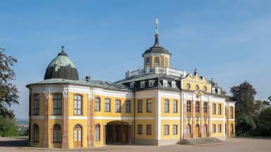 A large yellow building with a dome and a smaller tower, surrounded by a grassy area.