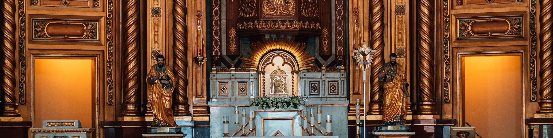 Interior de una iglesia ornamentada con un altar central, pinturas religiosas y un techo abovedado.