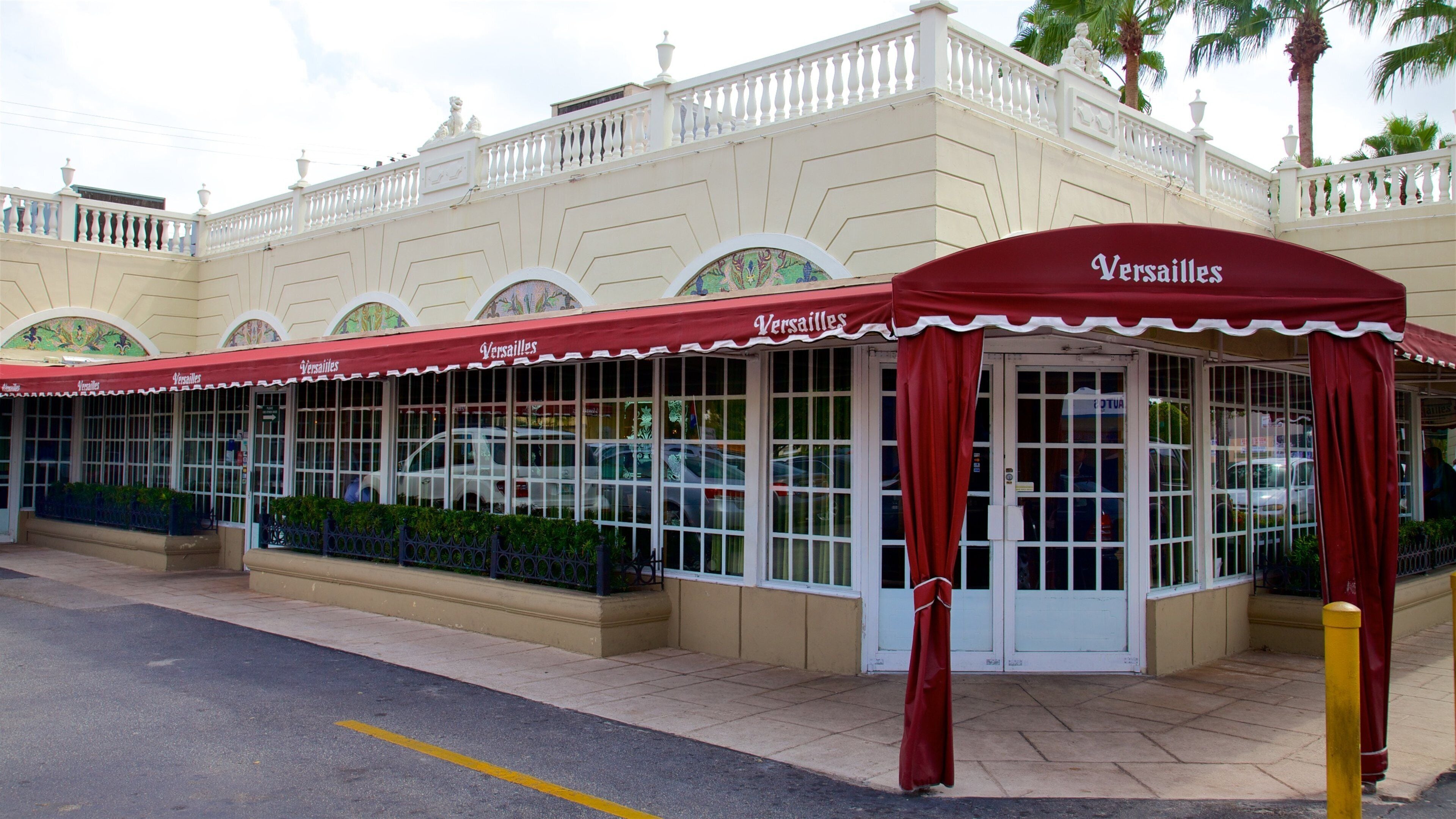 A building with a red awning labeled "Versailles" and a white fence.