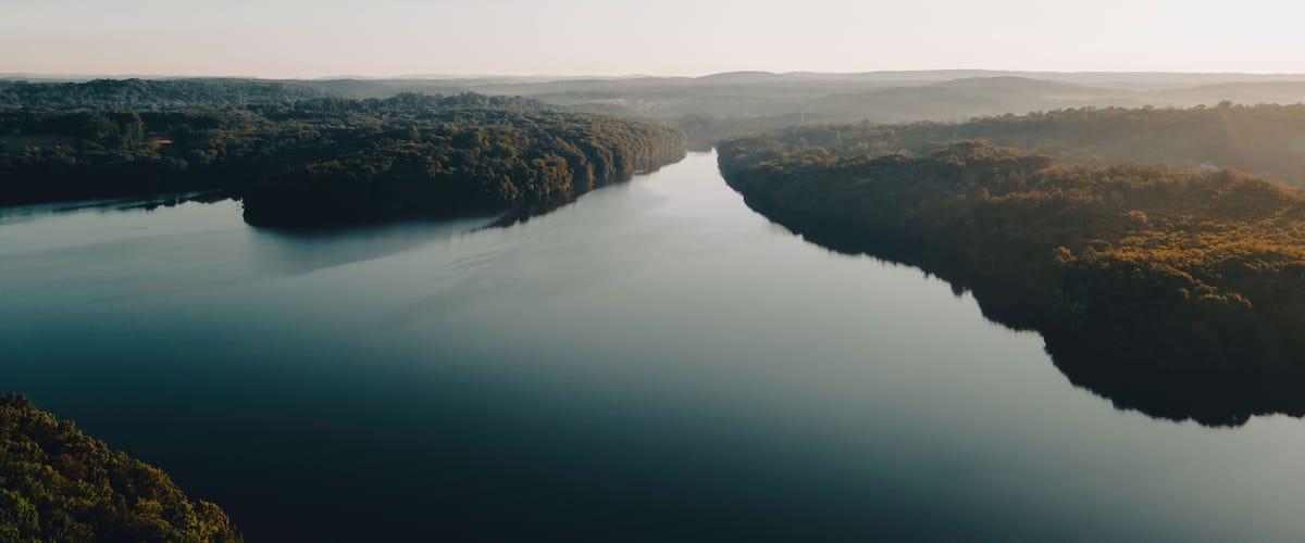 A river winding through a forested valley with hills in the distance.
