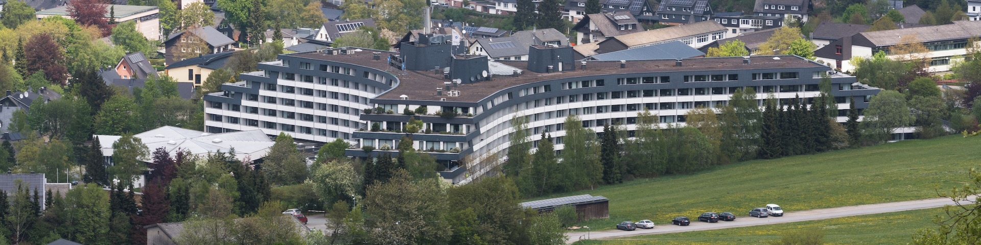 Un complejo moderno de edificios rodeado de abundante vegetación y casas residenciales.