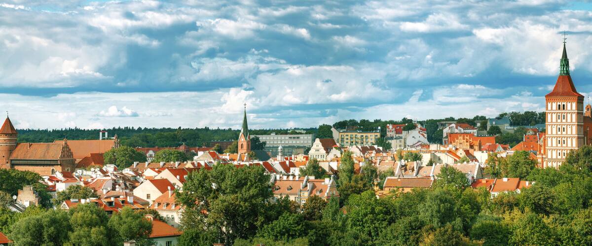 A historic town with red-roofed buildings, a prominent church tower, and a large church with a green spire.