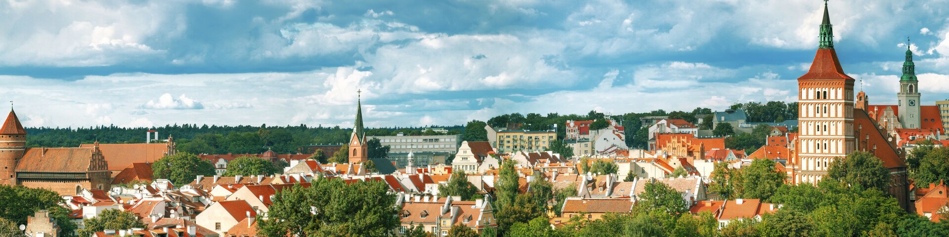 A historic town with red-roofed buildings, a prominent church tower, and a large church with a green spire.