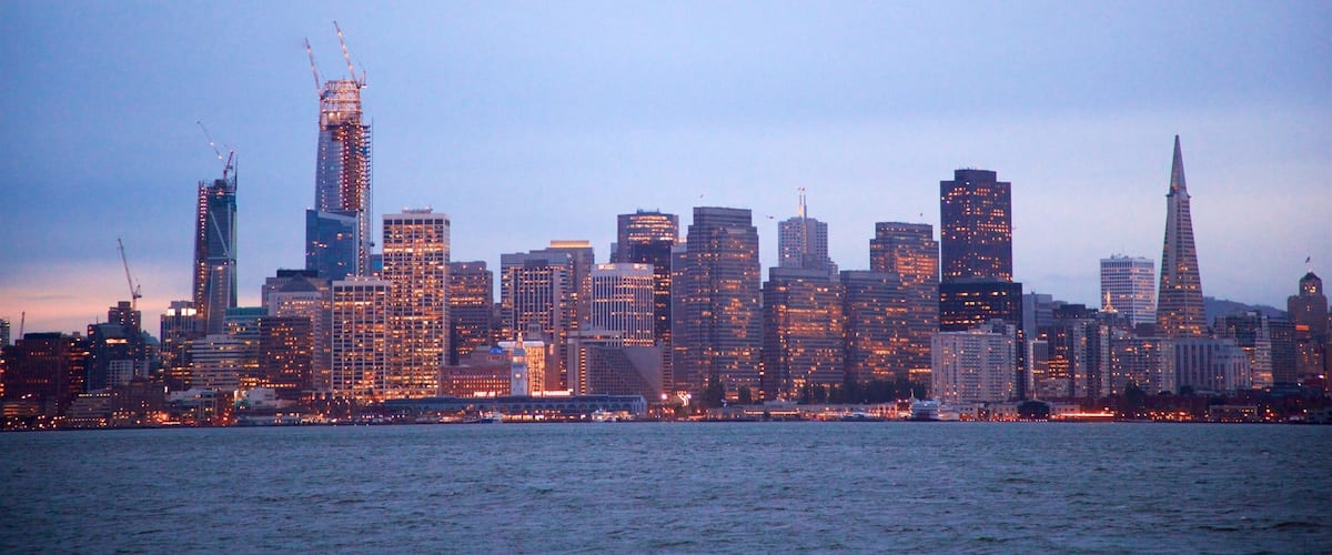 A city skyline with numerous high-rise buildings and a construction crane.