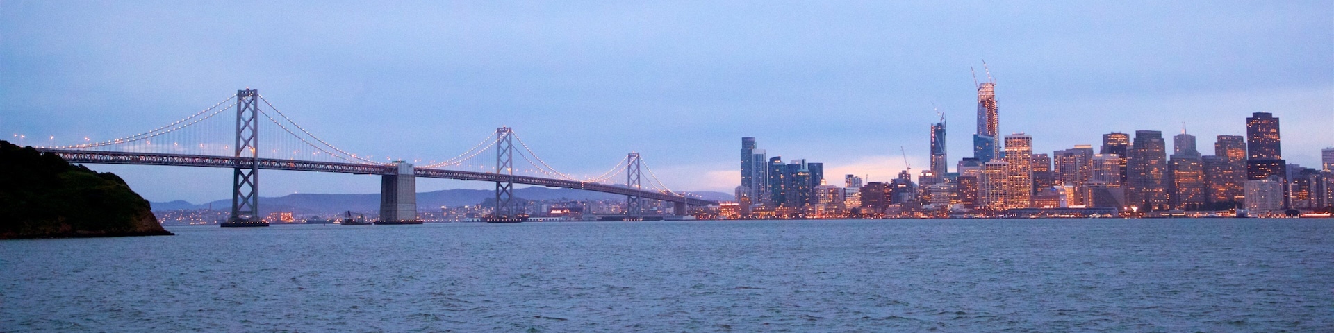 Uma ponte atravessa um corpo d'água, com o horizonte urbano ao fundo.