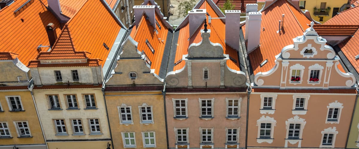 A row of colorful buildings with orange tiled roofs and ornate facades.