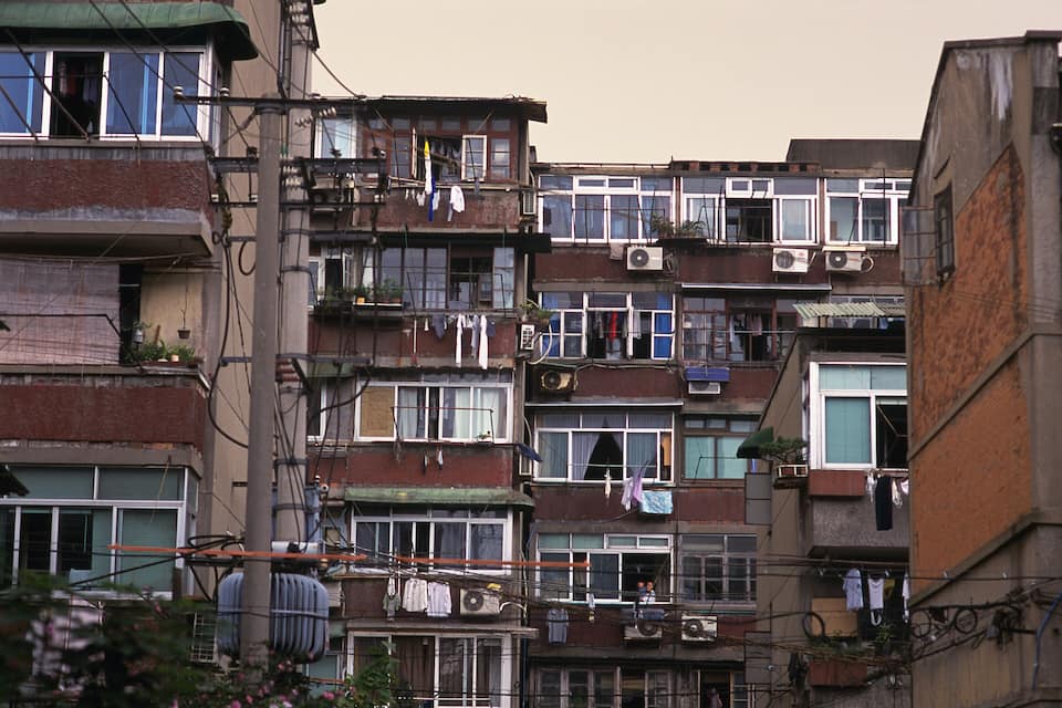 Zona residencial urbana densa amb edificis d'altes plantes, balcons visibles i roba penjada.