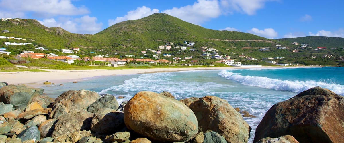 A coastal town with a beach, rocky shoreline, and a mountain in the background.