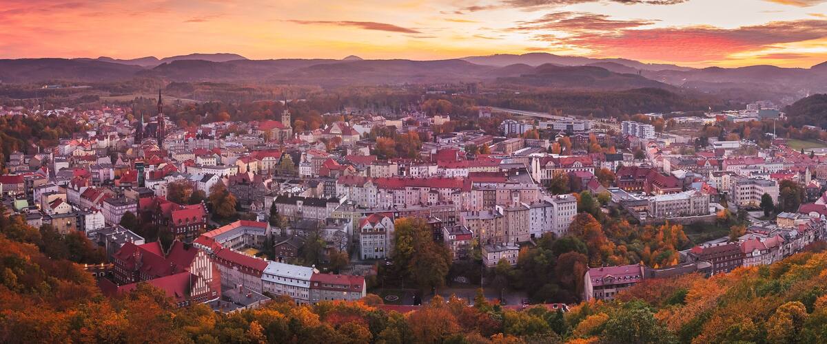 A cityscape with autumn foliage, historic buildings, and a river.