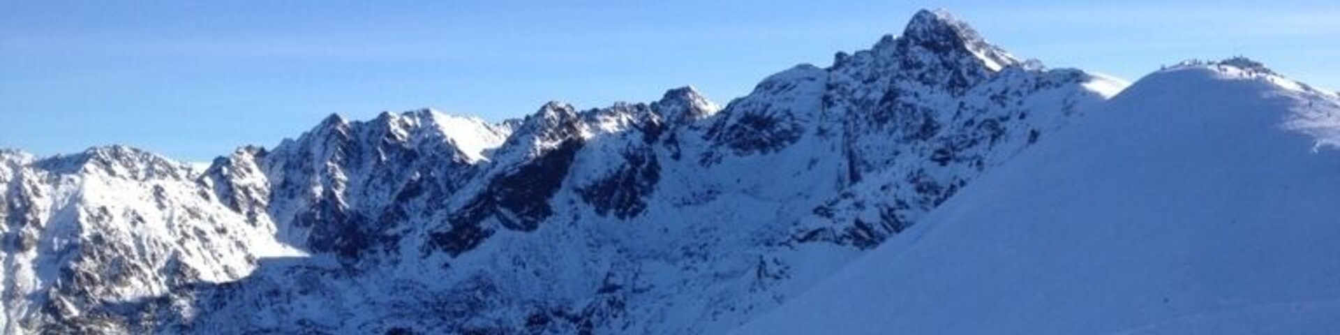 Uma cordilheira coberta de neve sob céus azuis límpidos.