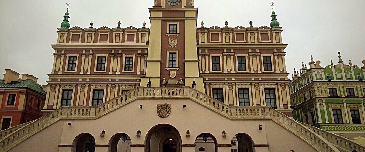 A historic building with a central clock tower and a staircase leading to an entrance.