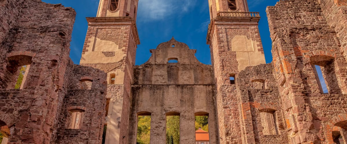 An ancient stone building with two bell towers and arched windows.