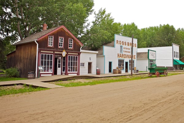 Une ville historique avec des bâtiments en bois, notamment une quincaillerie et un magasin Ross Bros.