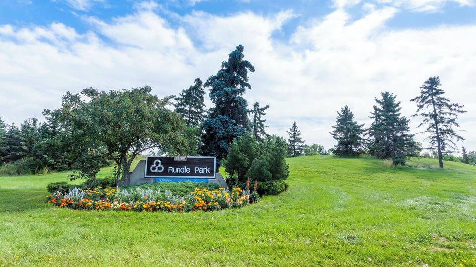A sign for Rundle Park with a grassy area and trees in the background.