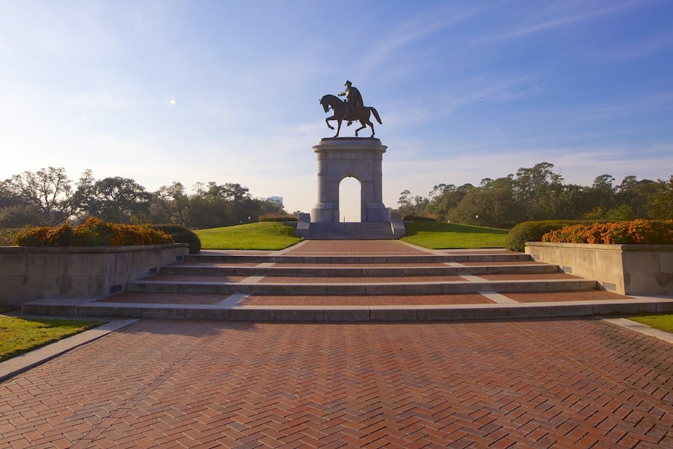 A statue of a man on horseback on a pedestal with steps leading up to it, surrounded by greenery and a clear sky.