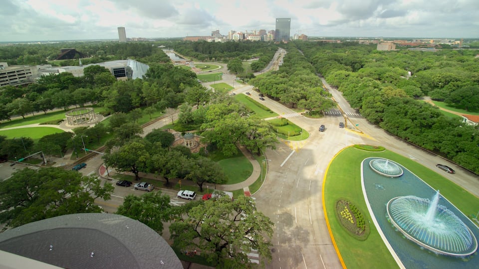 A city park with a fountain, roads, and surrounding buildings.