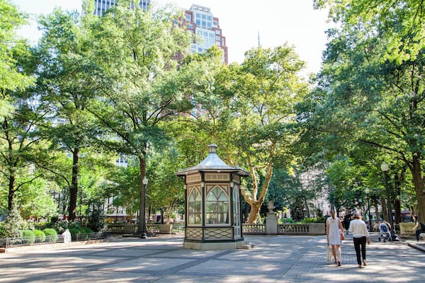 Ein Park mit einem Kiosk, Bäumen und einem gepflasterten Weg.