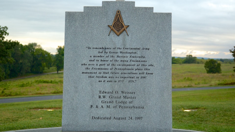 A granite monument with a Masonic symbol and a dedication inscription.