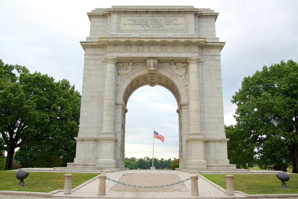 A large stone arch monument with an American flag in front.