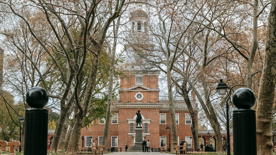 A historic building with a clock tower, surrounded by trees and benches.