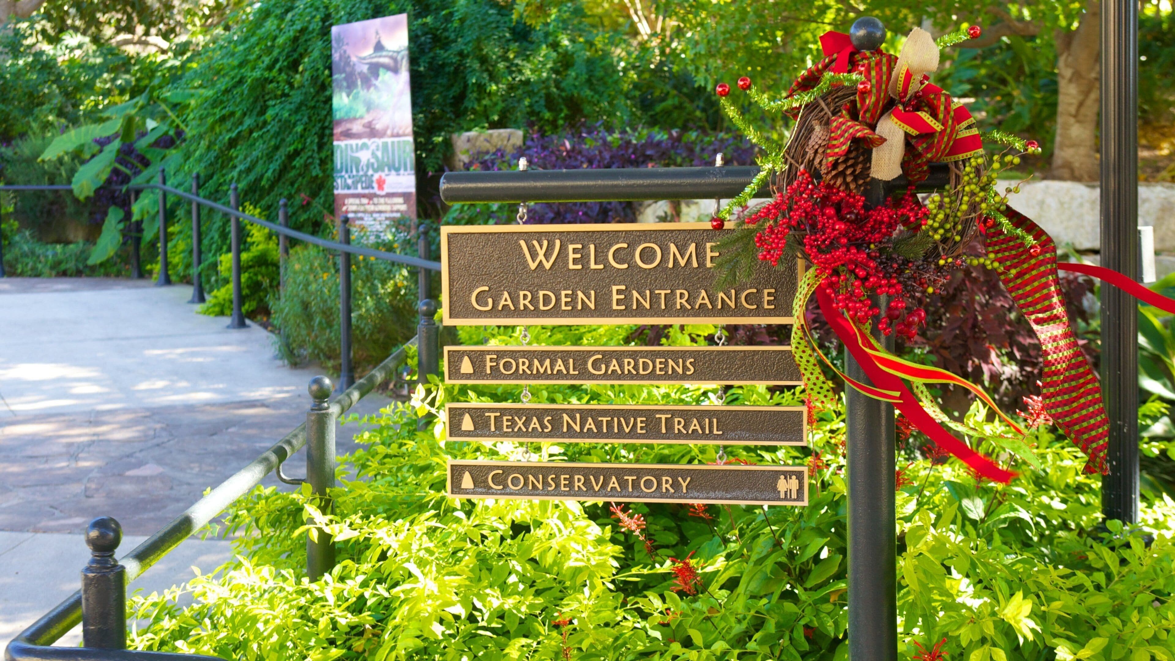 Señal de entrada al jardín con indicaciones hacia los Jardines Formales, el Sendero de Plantas Nativas de Texas y el Conservatorio.