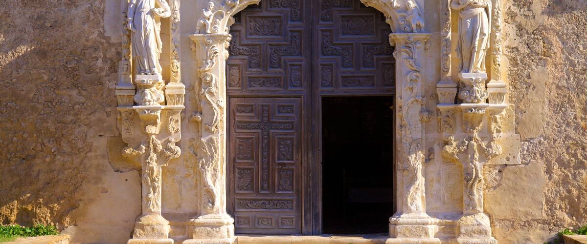 A large ornate door with intricate carvings and statues flanking it.