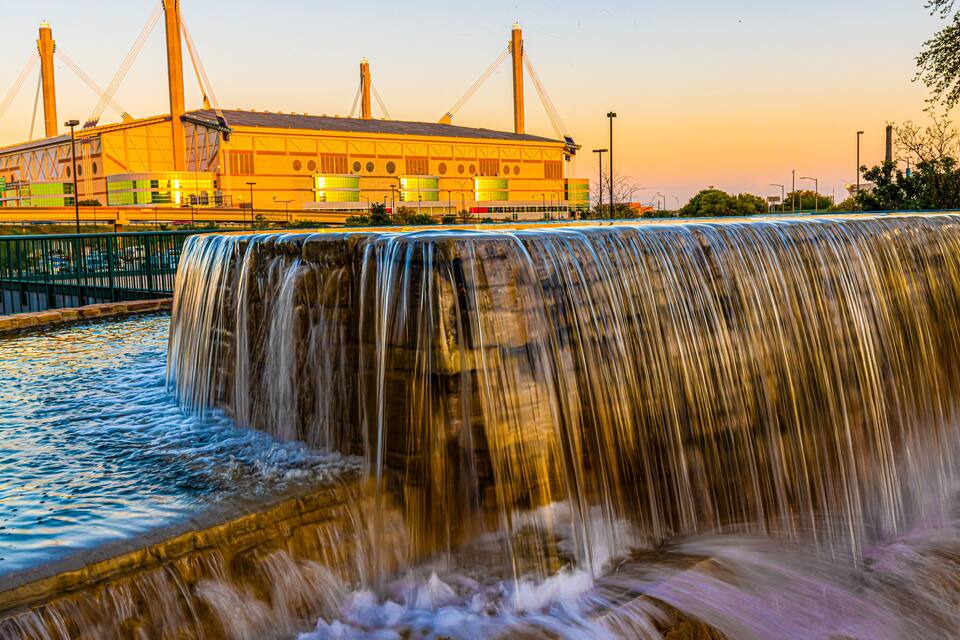 Uma cascata em frente a um grande edifício industrial com guindastes.