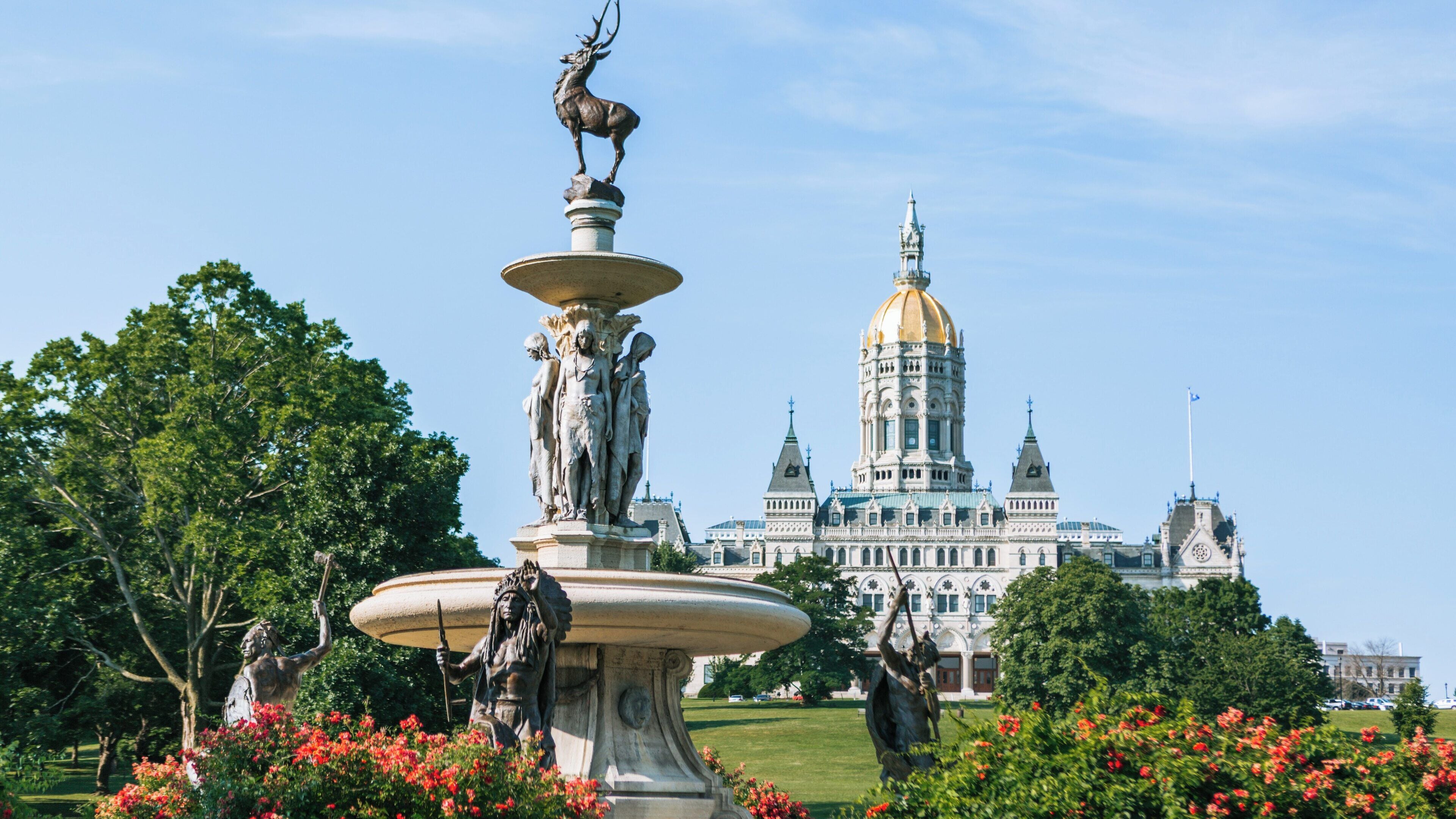 Bushnell Park features a historic fountain and the Connecticut State Capitol in Hartford, Connecticut on a clear day