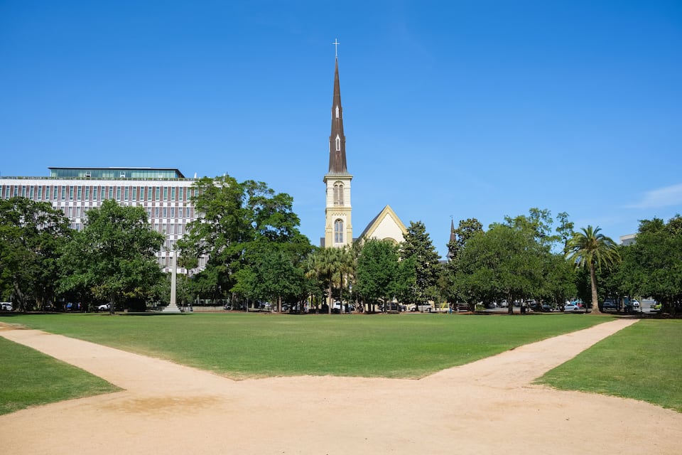 A park with a church and a tall building in the background.