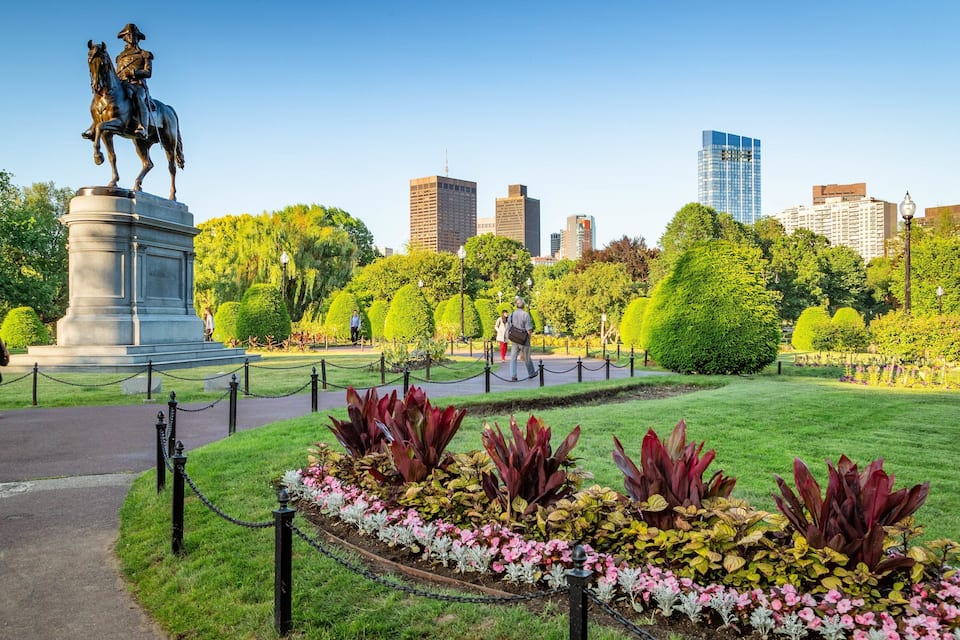 A statue of a man on horseback in a park with manicured lawns and flower beds.