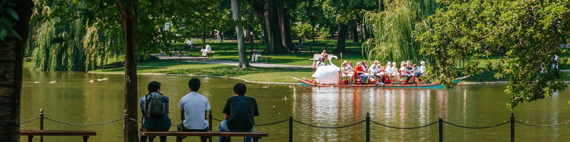 A park with a lake, benches, and a swan boat.