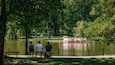 Um parque com lago, bancos e um barco cisne.