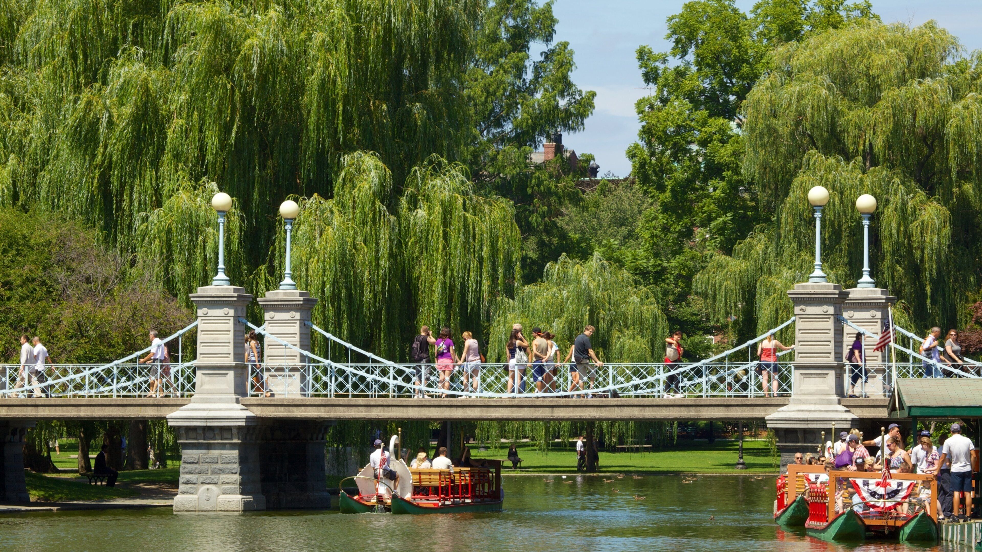 Uma ponte com pessoas caminhando e um barco na água.