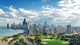 Une vue sur les gratte-ciel d’une ville, avec une rivière, des espaces verts et un terrain de baseball.