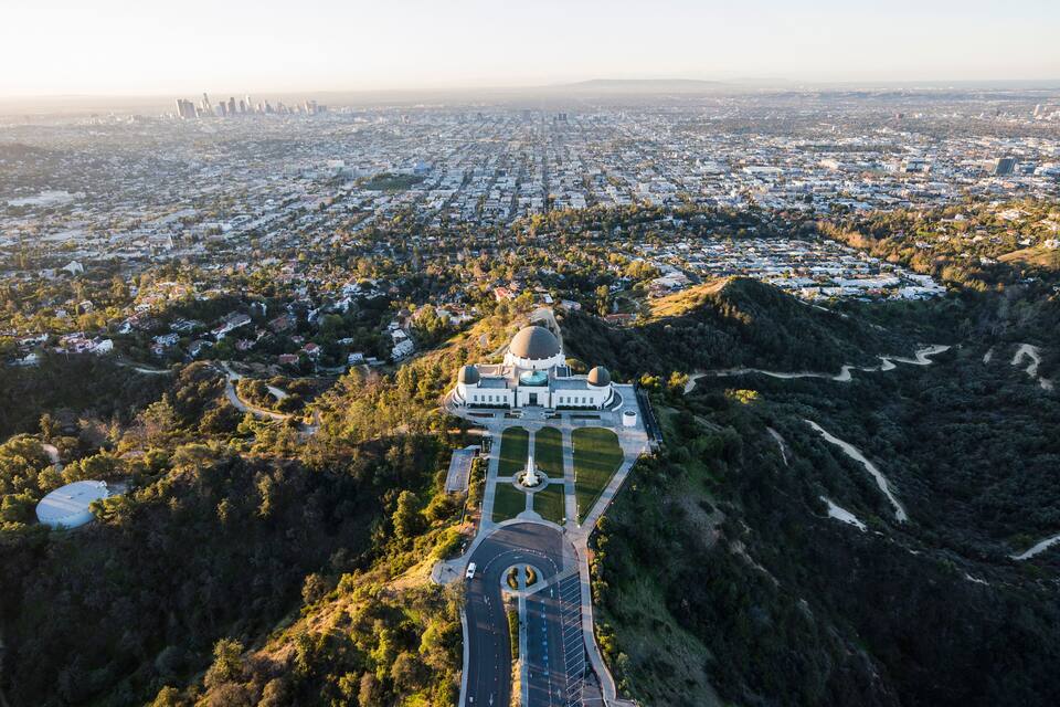 An aerial view of a city with a prominent domed building surrounded by greenery.