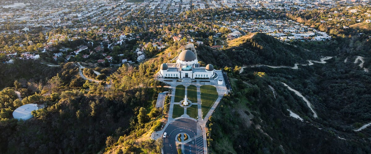 An aerial view of a city with a prominent domed building surrounded by greenery.
