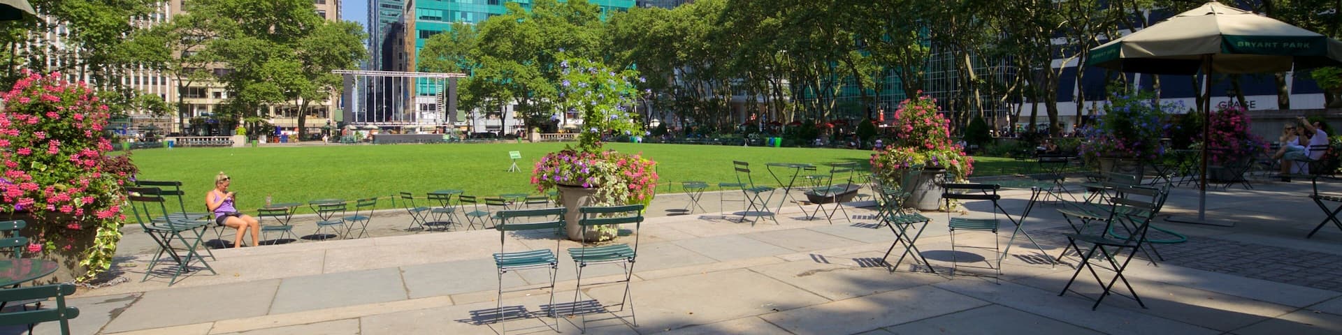 A park with green grass, trees, and outdoor seating.
