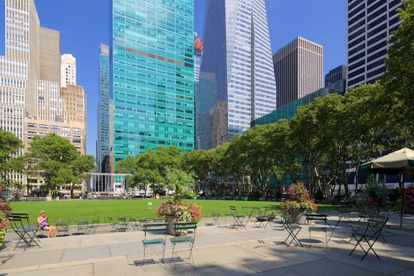 Un parc avec de l’herbe verte, des arbres et des espaces aménagés pour s’asseoir à l’extérieur.