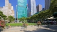 A park with green grass, trees, and outdoor seating.
