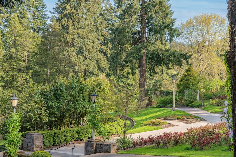 A park with a winding path, stone benches, and lamp posts.