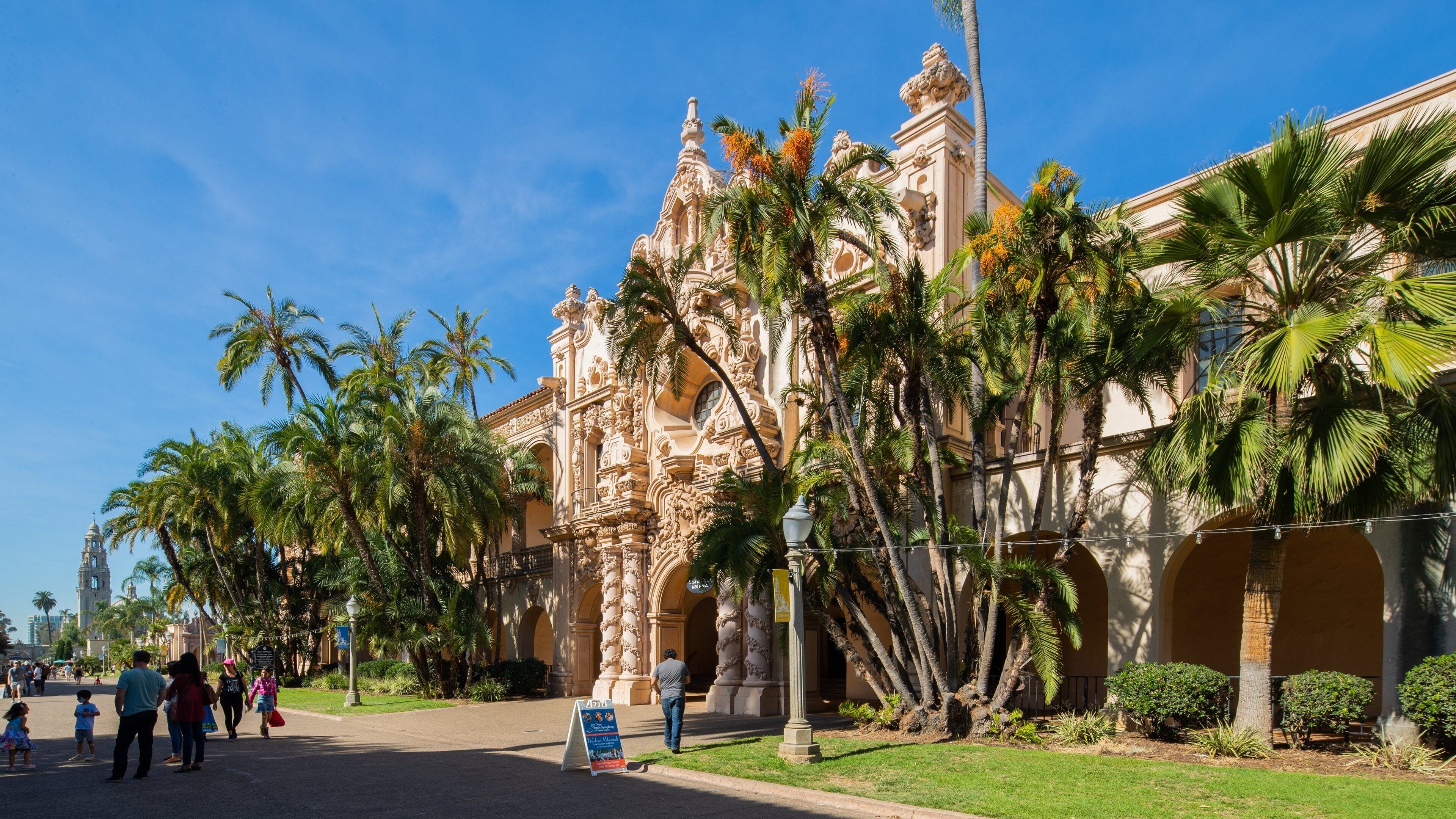 A historic building with ornate architecture, palm trees, and a clear blue sky.