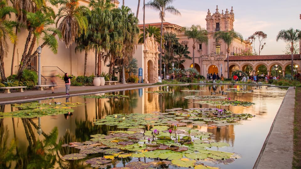 A historic building with ornate architecture and a reflective pond with lily pads.